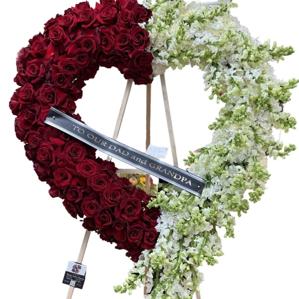 Heart-shaped floral tribute of red roses and white flowers on an easel