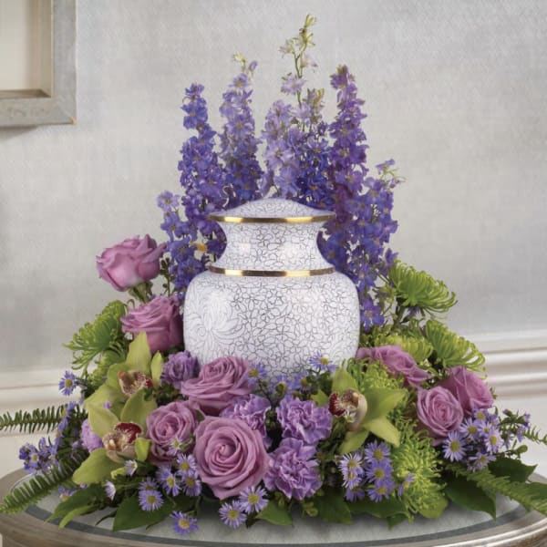 Purple floral arrangement around a white urn vase
