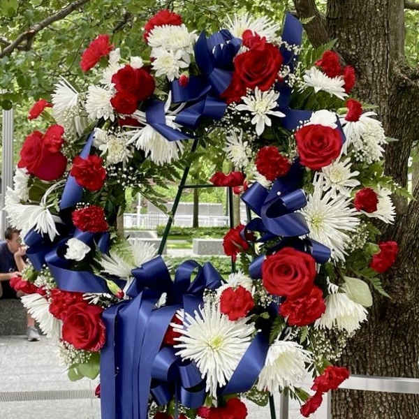 Large wreath of red and white flowers with blue ribbons on an easel