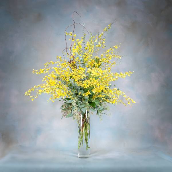 Tall yellow floral arrangement in a clear glass vase