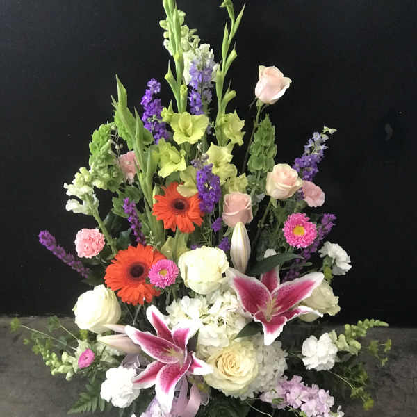 Tall mixed floral arrangement with lilies, roses, and gerbera daisies