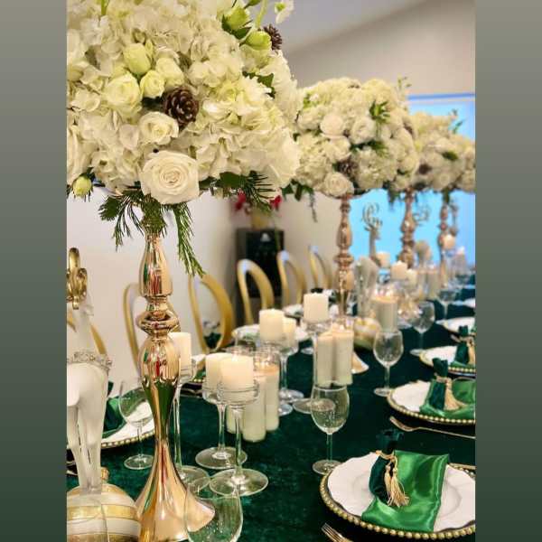 White floral centerpieces on gold stands above a green-and-gold table setting