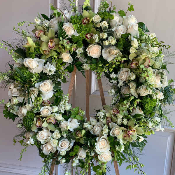 Large floral wreath on a wooden easel with white and green blooms