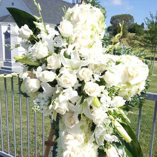 Large white funeral spray on an easel outdoors