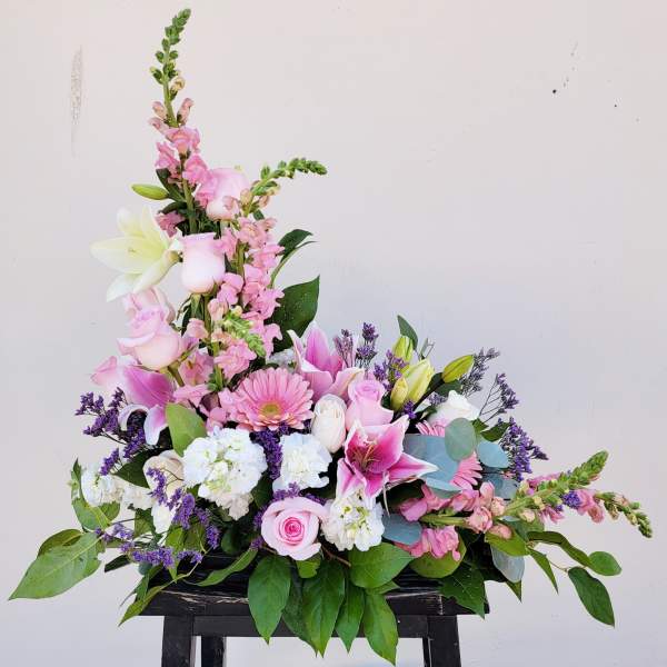 Pink and white floral arrangement with lilies and roses in a low container