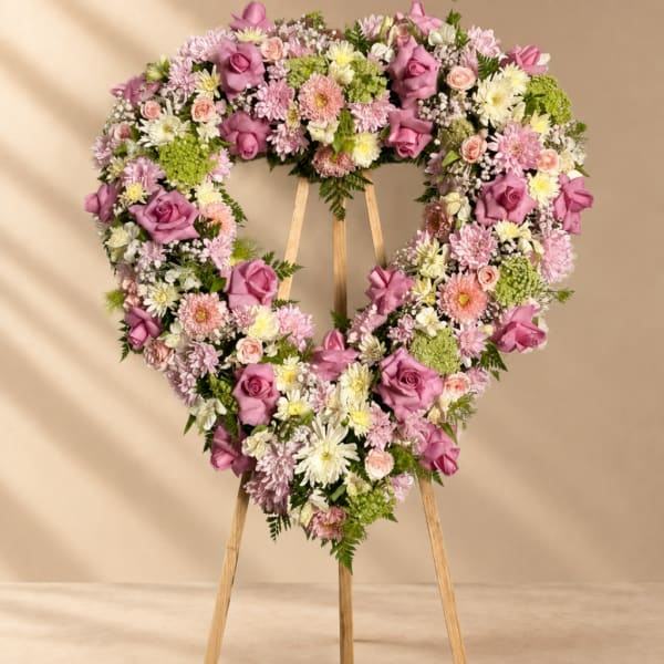 Heart-shaped floral wreath on a wooden easel with pink and white flowers