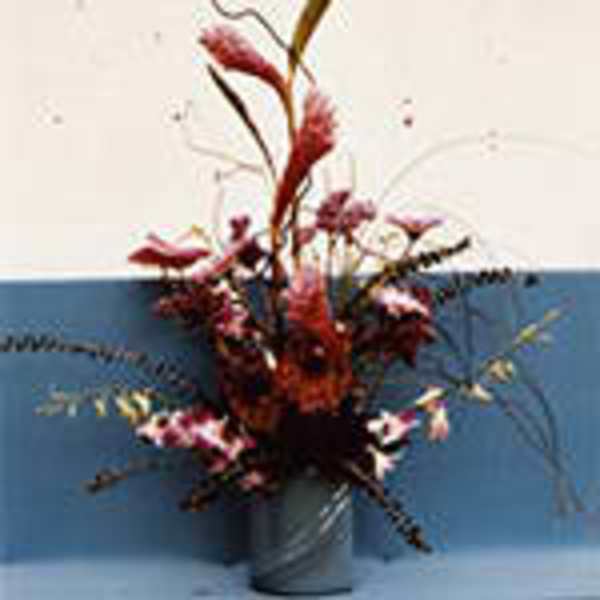 Tall red and pink floral arrangement in a blue vase