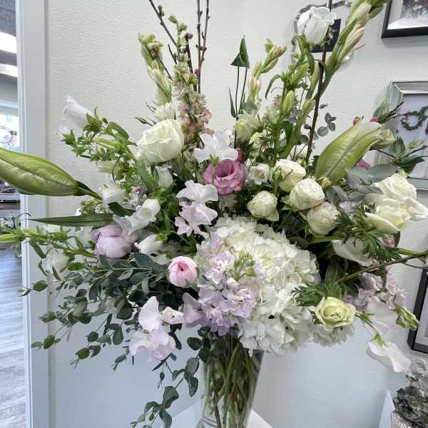 Tall bouquet of white and pale pink flowers in a clear glass vase