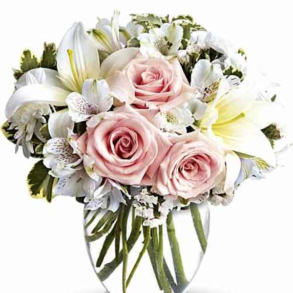 Pink roses and white lilies arranged in a clear glass vase