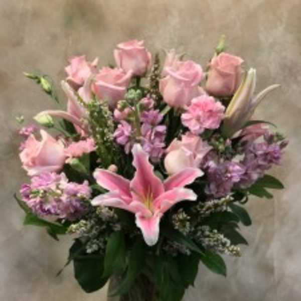 Pink roses and lilies arranged in a glass vase