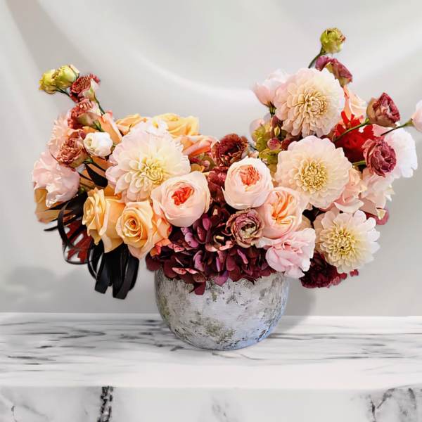 Bouquet of peach and cream flowers in a round vase