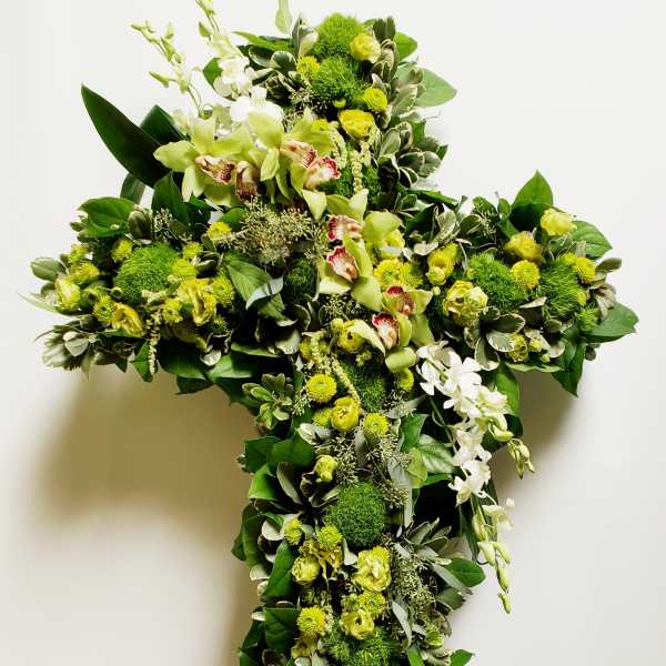 Green floral cross on an easel with white orchids and yellow blooms