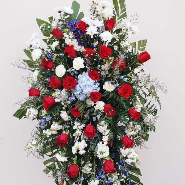 Large standing floral spray with red roses, white blooms, and blue accents
