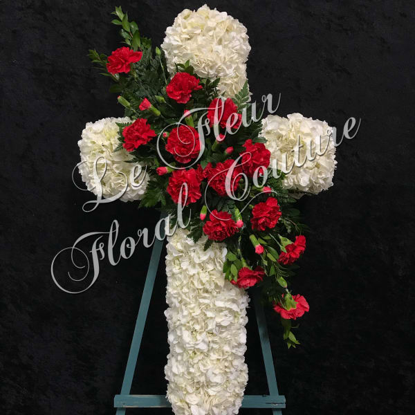 White floral cross with red carnations on an easel