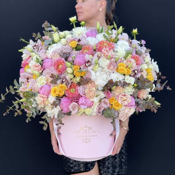 Large pastel bouquet in a pink hatbox held by a woman
