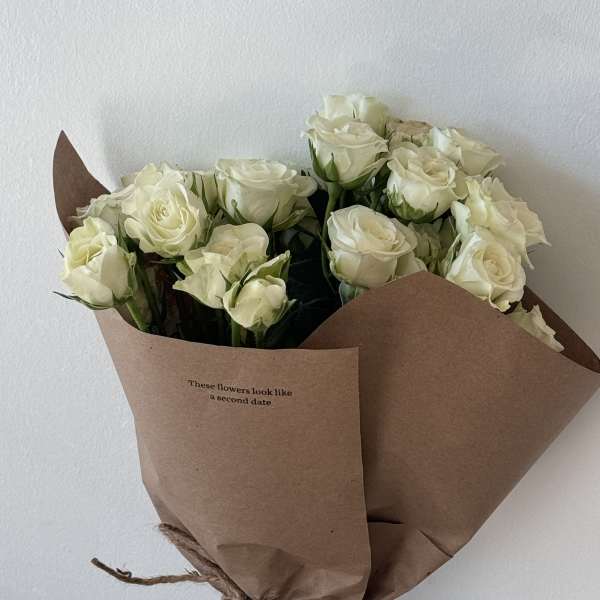 Bouquet of white roses wrapped in brown paper