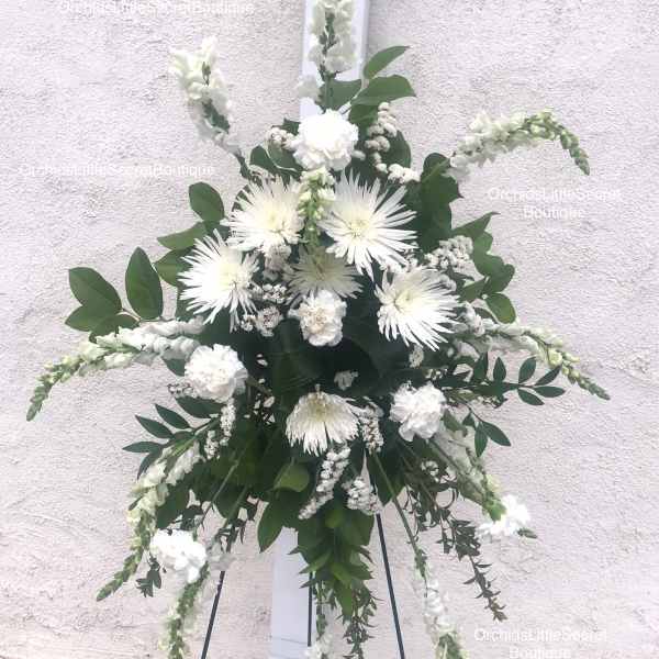 White floral standing spray on a black easel