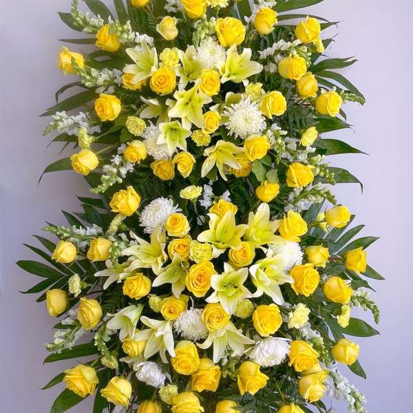 Standing floral spray with yellow roses, white lilies, and white mums