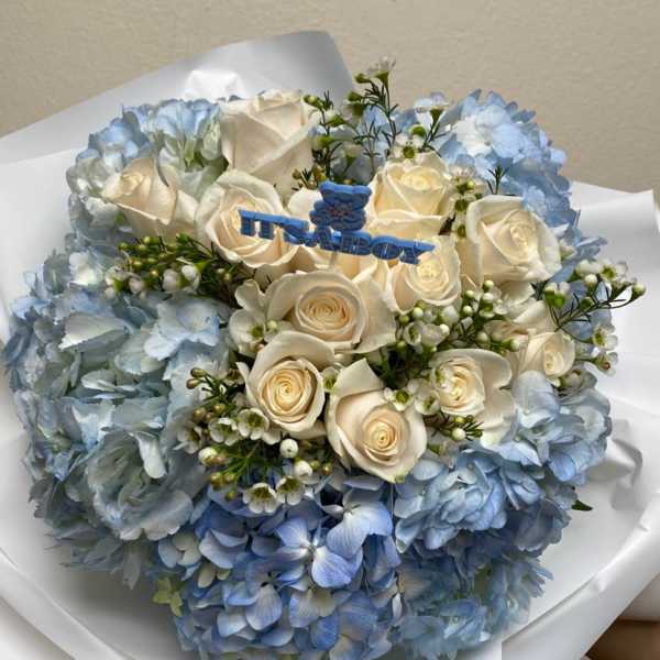 Blue hydrangea bouquet with white roses and a baby boy topper