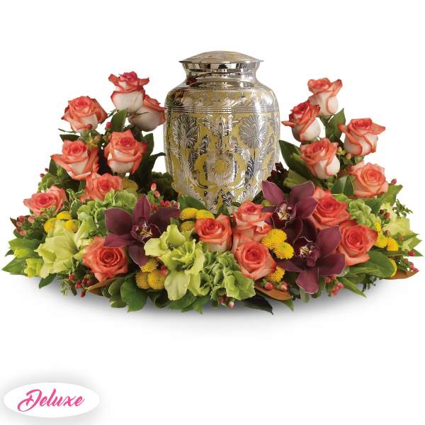 Floral urn arrangement with coral roses and purple orchids around a silver urn