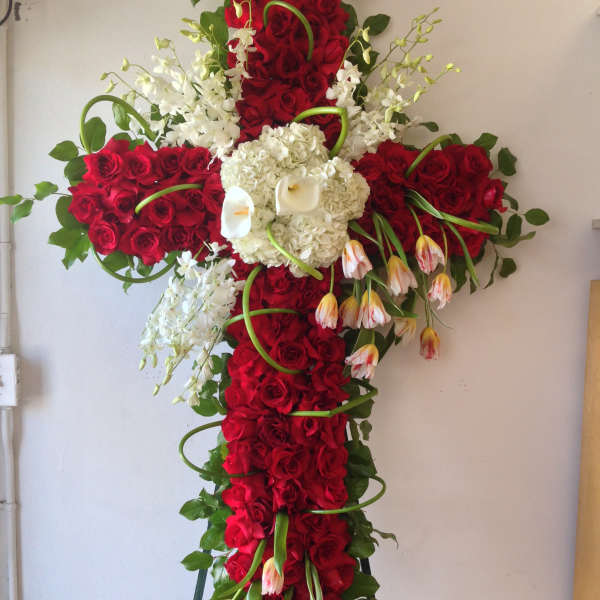 Large cross-shaped floral spray with red roses, white orchids, and calla lilies