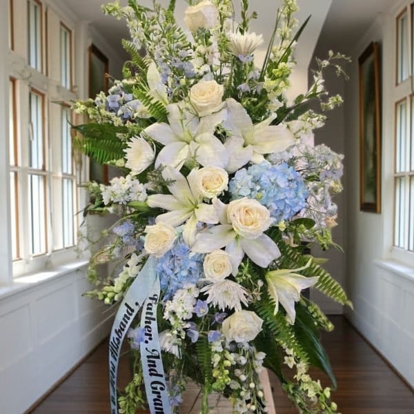 Large white and blue floral standing spray with lilies and roses
