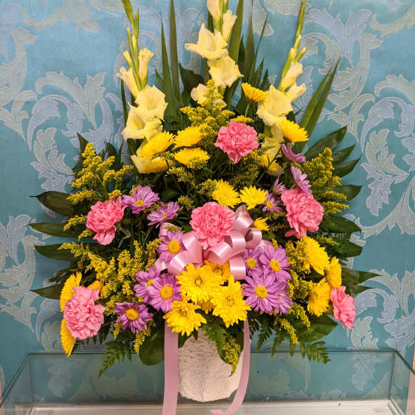 Tall floral arrangement with yellow, pink, and purple blooms in a white vase
