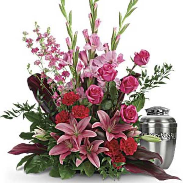 Pink lilies and roses arranged beside a silver urn