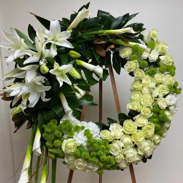 Floral wreath with white lilies, cream roses, and green pom-pom blooms