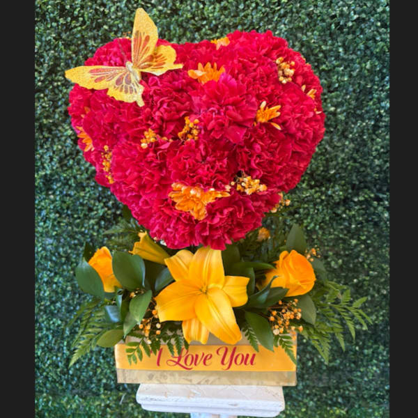 Heart-shaped red carnation arrangement with yellow flowers and a butterfly topper