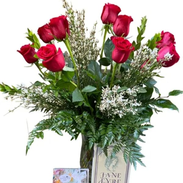 Red roses in a glass vase with greenery and a greeting card