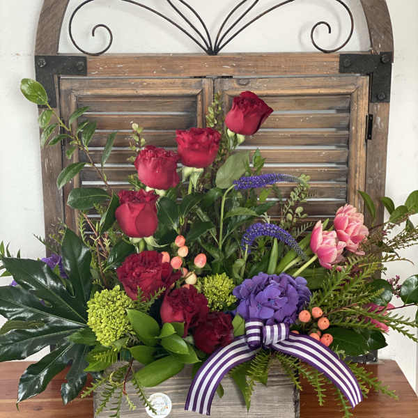Mixed bouquet with red roses, purple hydrangea, and pink tulips in a wooden box