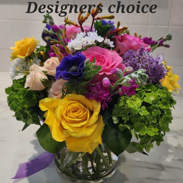 Mixed bouquet of roses, hydrangeas, and purple blooms in a glass vase