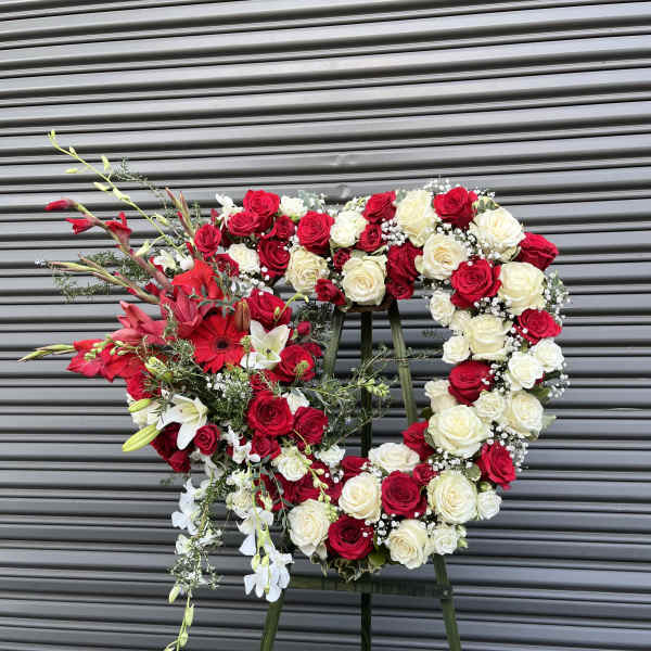 Heart-shaped red and white rose wreath on a stand