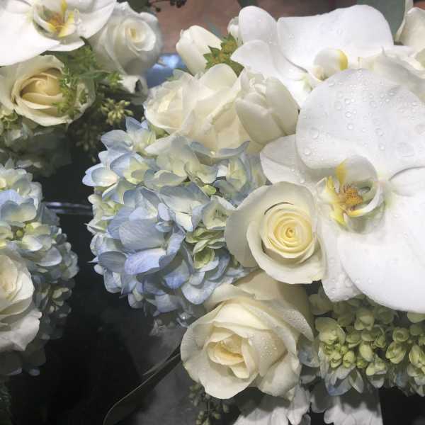 White orchids and roses with blue hydrangeas in a bouquet