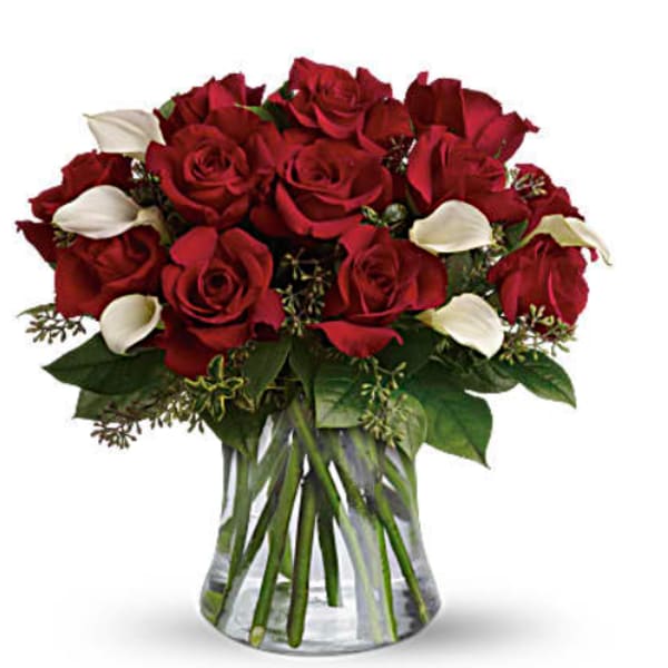 Bouquet of red roses with white calla lilies in a clear glass vase