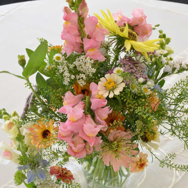 Mixed pastel flower arrangements in clear glass vases on a white tablecloth