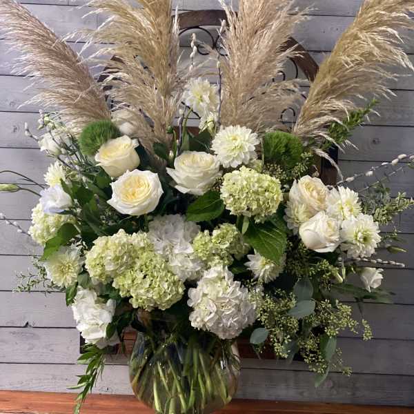 White floral arrangement with pampas grass in a glass vase
