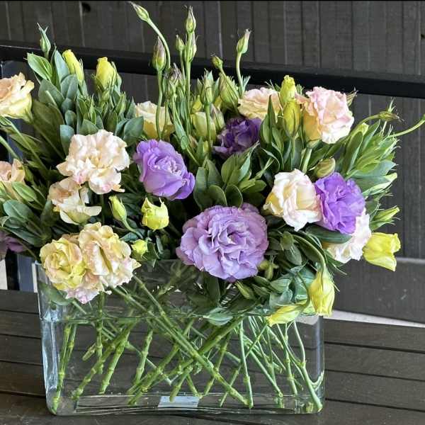 Mixed pastel flowers arranged in a clear rectangular vase