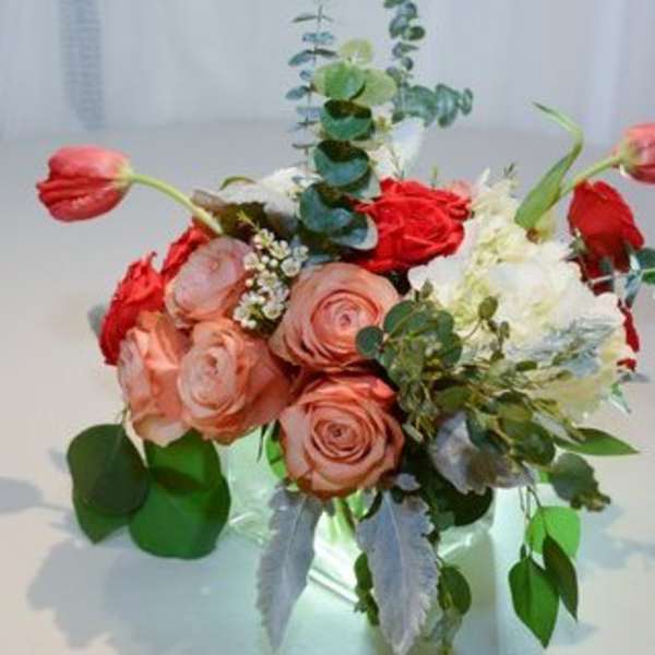 Bouquet of pink and red roses with white flowers in a clear vase