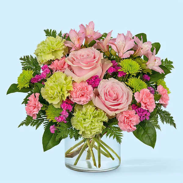 Pink roses and mixed flowers arranged in a clear glass vase