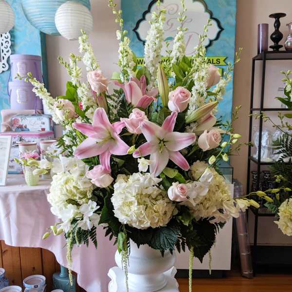 Large pink lily and rose arrangement in a white vase