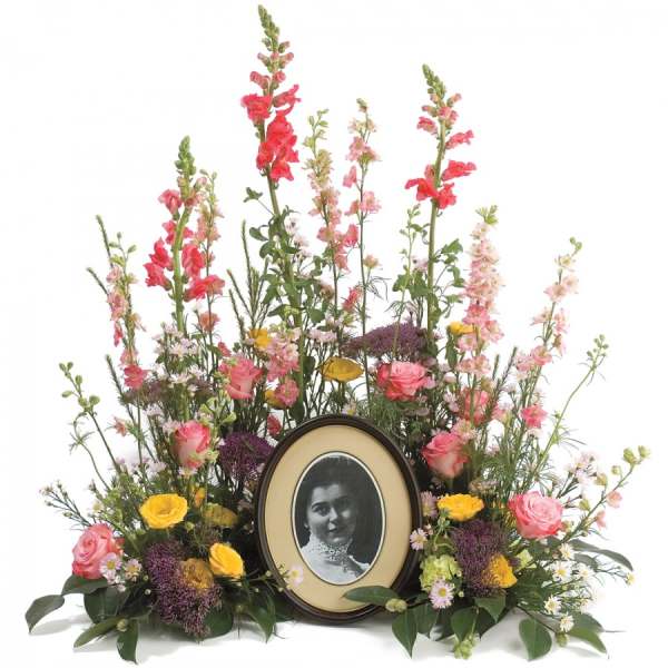 Floral memorial arrangement with a framed portrait in the center