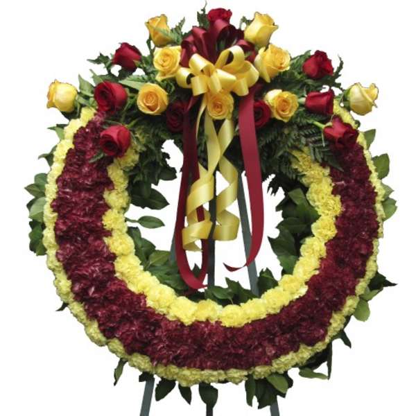 Circular funeral wreath with red and yellow flowers and ribbon