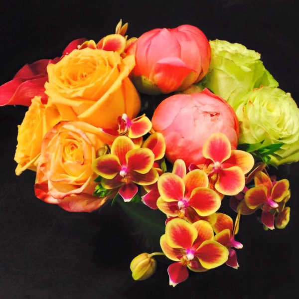 Bouquet of orange and pink roses with red-yellow orchids on a black background