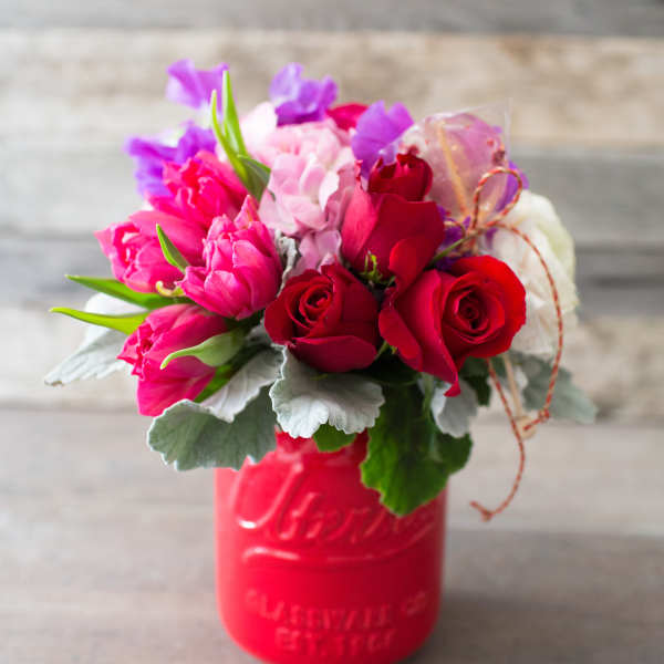 Bouquet of red and pink roses in a red mason jar