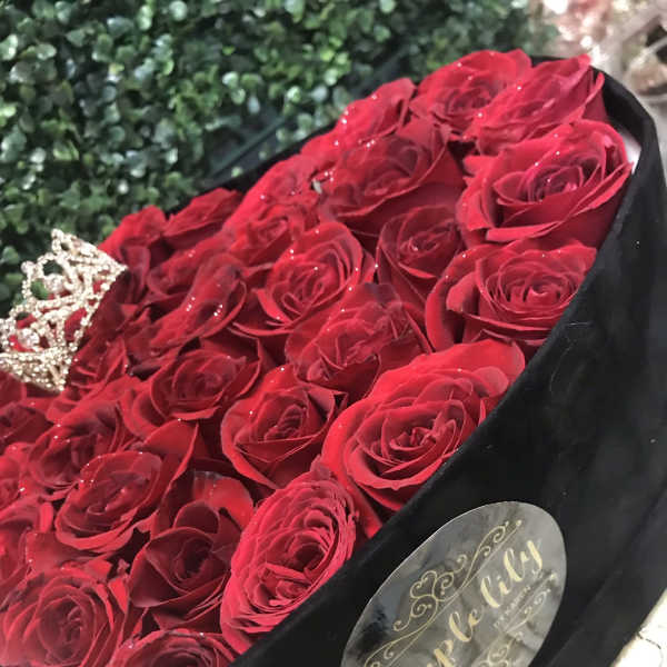 Bouquet of red roses in a black box with a small crown decoration
