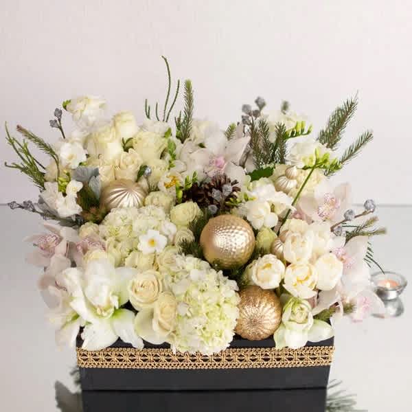Cream and white floral arrangement in a black box with gold ornaments