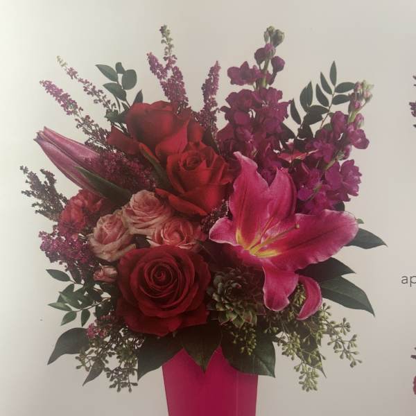 Bouquet of red roses and pink lilies in a tall pink vase