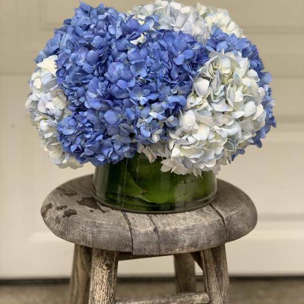 Blue and white hydrangeas in a green glass vase